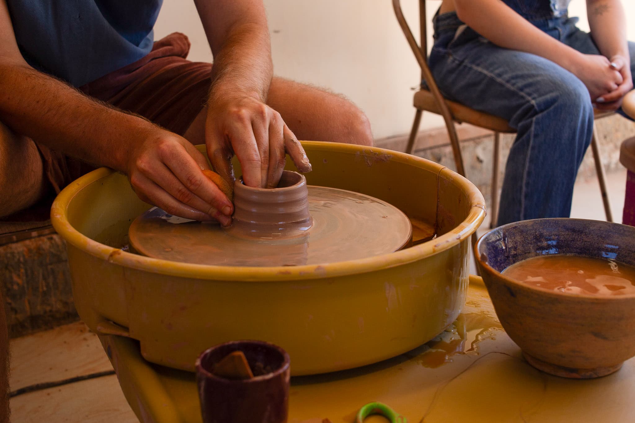 Hands shaping clay on pottery wheel